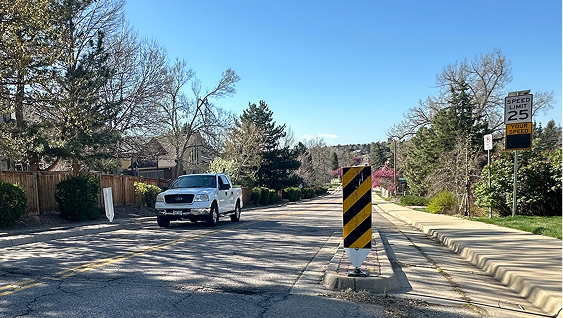 Concrete curbs narrow the roadway to reduce speeds along the roadway.